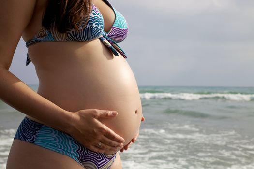 Closeup of pregnant belly with hands holding it