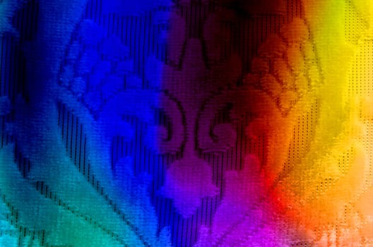 A background of a fabric with floral design, lit in colorful lights.