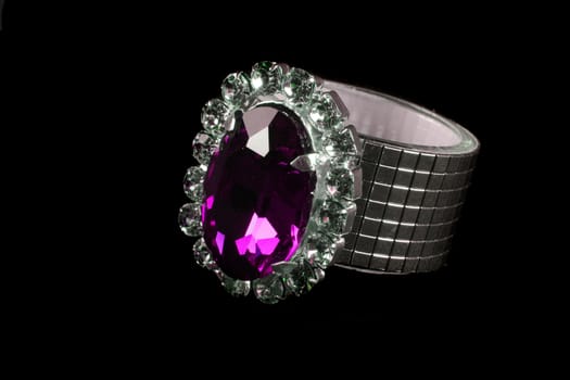A ring shaped tissue holder studded with precious jewels, on black studio background.
