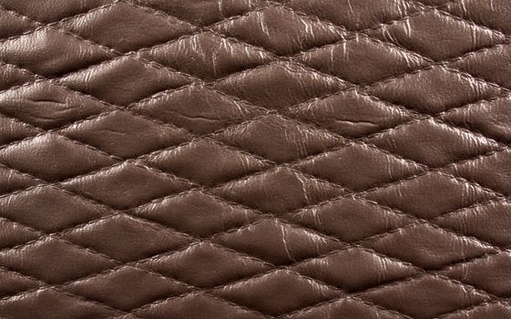 A background of a diamond shaped pattern on a brown leather fabric.