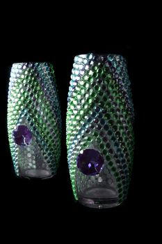 Beautiful designer vases studded with colorful artificial jewels, on black studio background.