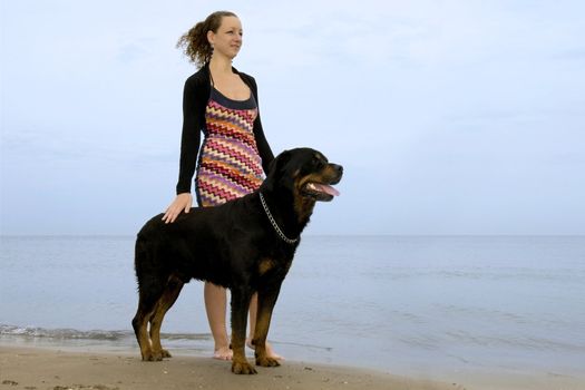 portrait of a purebred rottweiler and young woman on the beach