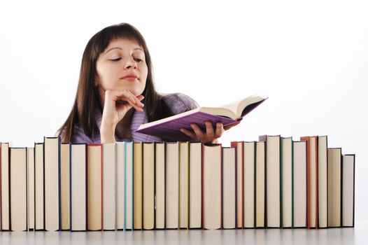 young woman reading a book behind a big pile of books 