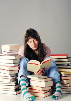 Cute girl studying with a big stack of books