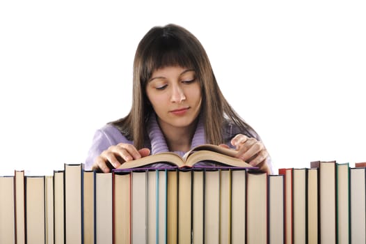 young woman reading a book behind a big pile of books 