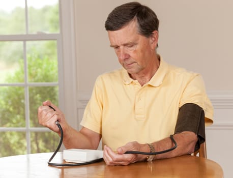 Senior caucasian retired male taking blood pressure at home