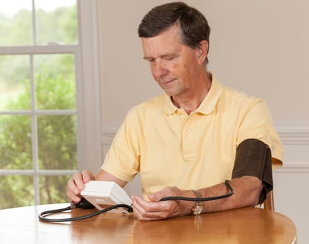 Senior caucasian retired male taking blood pressure at home