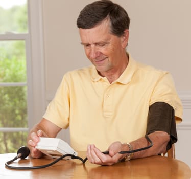 Senior caucasian retired male taking blood pressure at home