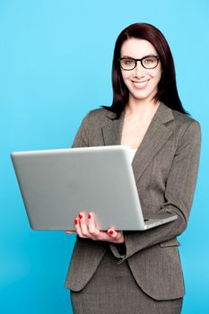Young corporate woman working on laptop isolated against blue