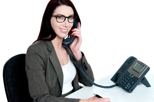 Young businesswoman holding phone receiver against white background
