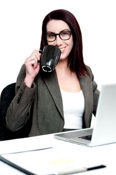 Corporate woman enjoying coffee at work desk. Time for a short break