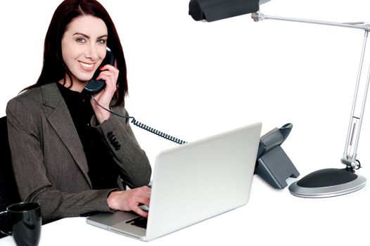 Female operator talking on phone and smiling. Actively working in office