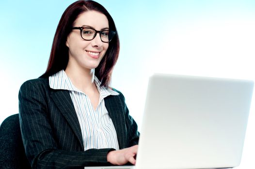 Young business executive working on laptop and smiling at camera