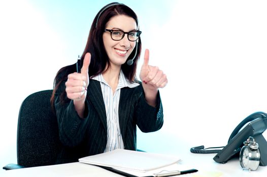 Cheerful female call centre operator gesturing double thumbs up in joy