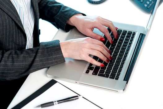 Females hands typing on laptop keypad. Cropped image. Busy office desk
