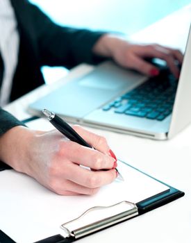 Closeup of woman copying data from laptop to notepad, Making important notes