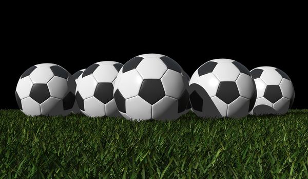 soccer balls on a green grass - black background