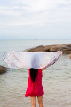 Girl wear red shirt holding Scarf at wind on the beach