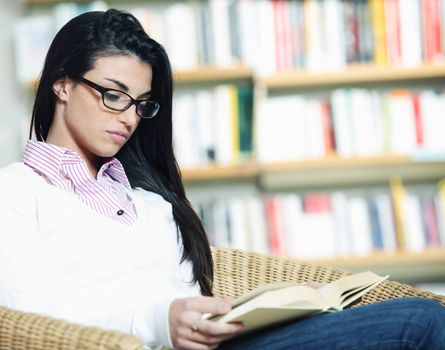 female student reading a book in library