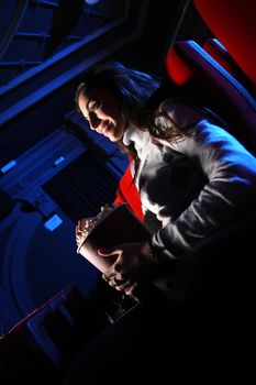 portrait of a girl in a movie theater a pretty young woman sitting in an empty theater, she eats popcorn and smiles