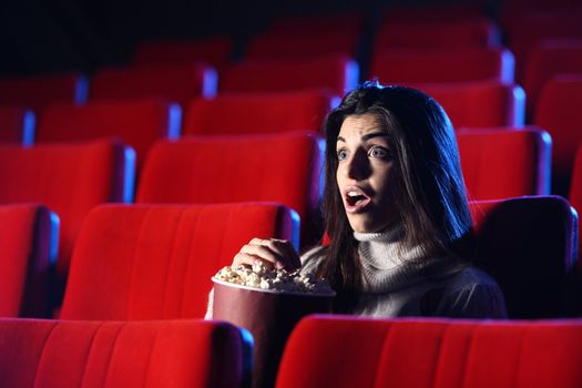 scary movie: portrait of a pretty girl in an empty theater, she has expression of surprise and fear on his face