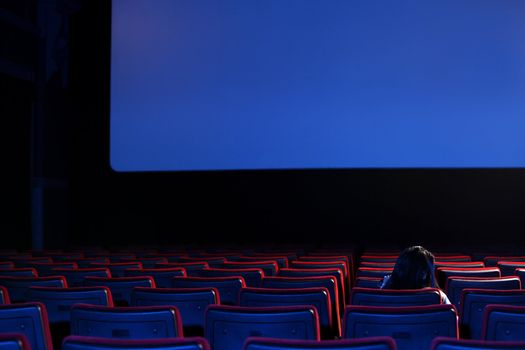 the end: youn woman  alone sitting in a empty movie theater,rear view