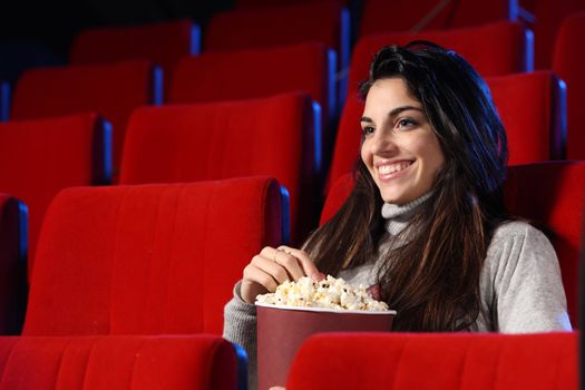 funny movie: portrait of a pretty girl in an empty theater, she eats popcorn and smiles