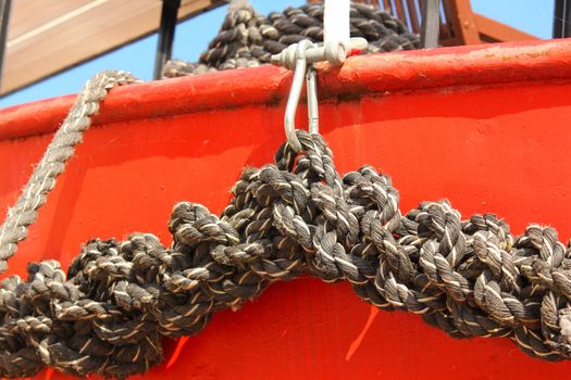 Close-up of an old frayed boat rope, on a red boat