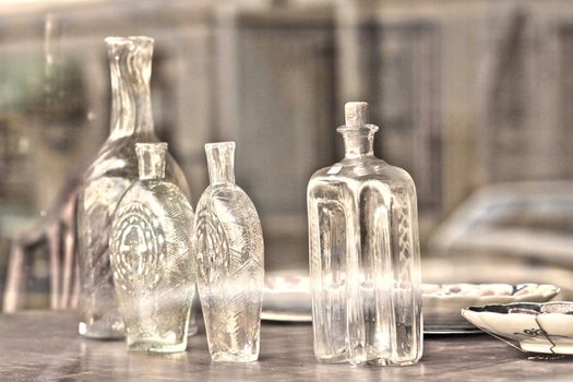 White glass bottles on a bench with porcelain plates