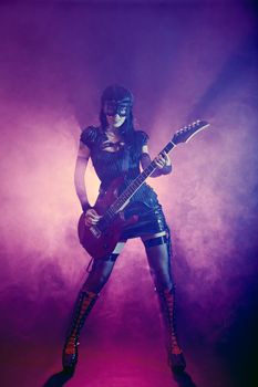 Goth girl in goggles plays guitar on the stage 