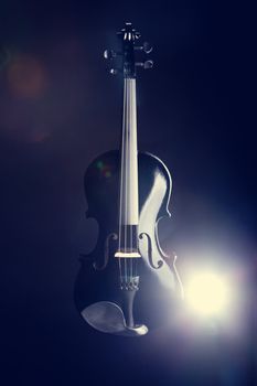 Modern black violin on deep blue background, studio shot 