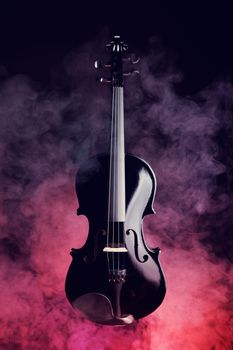 Elegant black violin in smoke on red and black background 