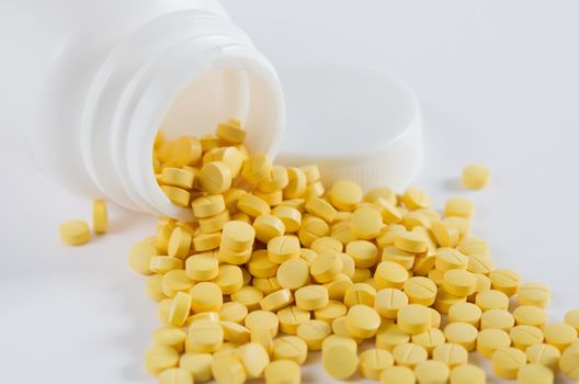 yellow medicine out of white bottle on white background
