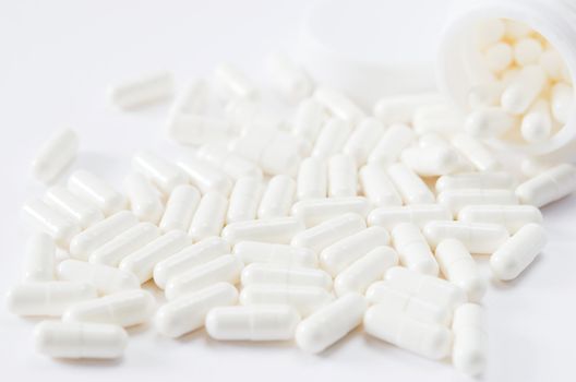 pills spilling out of pill bottle on white background