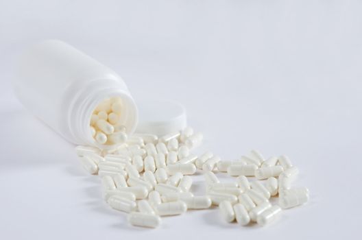 pills spilling out of  pill bottle on white background
