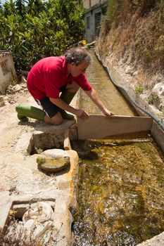 Kneeling at the irrigation ditch to get water