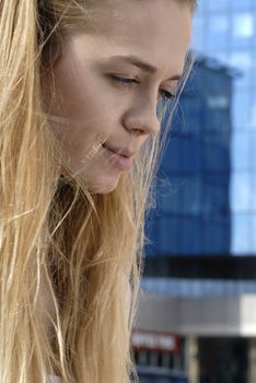 face of beautiful blonde young woman on a city background