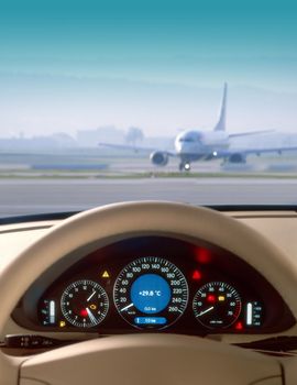 Wheel and dashboard of a car and view of airport