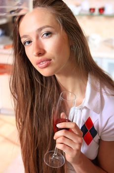 beautiful woman in white top in kitchen with glass of wine