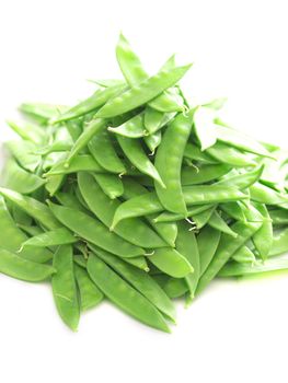 close up of a heap of snow peas on white