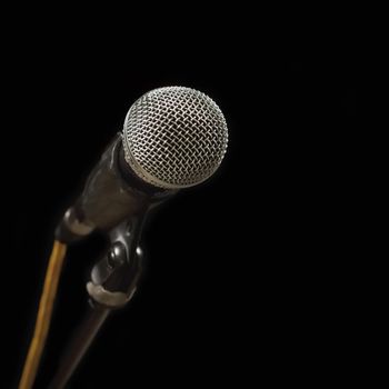 Classic black microphone on black stand. Isolated black background