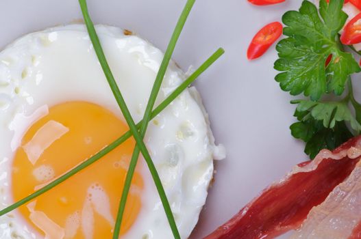 Fried Eggs Sunny Side Up with Bacon, Parsley and Lettuce closeup clipping path on gray plate
