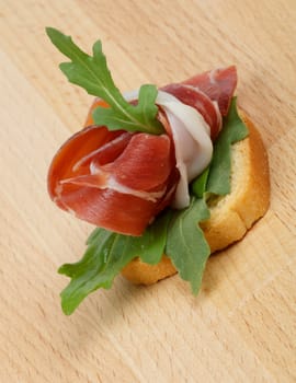 Jamon appetizer with greens isolated on wooden background