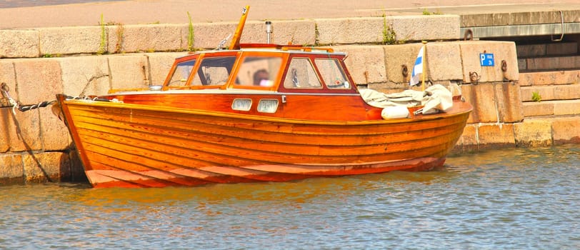 Shiny wooden boat, mooring in water at harbor