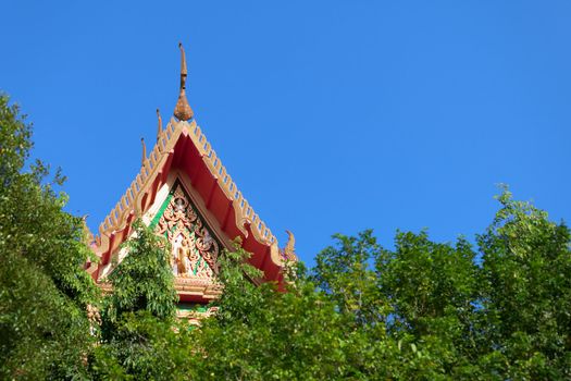 The roof of a Thai Buddhist monastery over the trees
