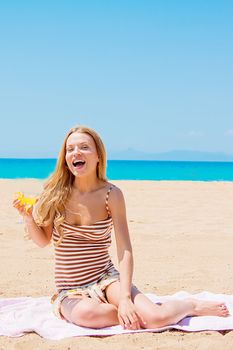 Photo of a young and beautiful woman who is resting on the beach and drink a drink from a glass