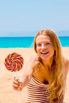 A young and beautiful woman with a lollipop resting on the beach