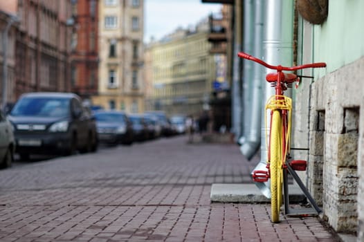 old yellow bicycle stands at the walls the city houses