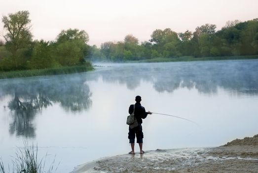 The silhouette of fisherman in morning river