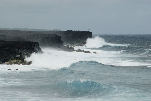 rugged coast line of hawaii's big island, huge waves crash against black volcanic cliffs at Kalapana